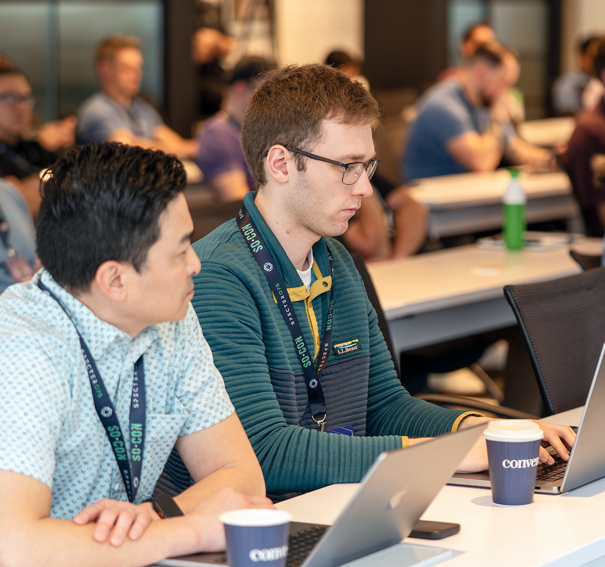 Two men working at a table on laptops